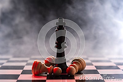 Chess queen defeats a batch of white pawns on a chessboard on a background with smoke Stock Photo