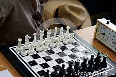 A chess set with special holes for travelers and for the blind is on the table next to the clock, sheriff`s hat and black glasses Stock Photo