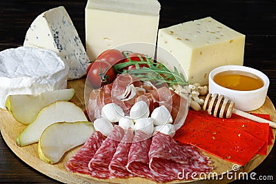 Chesse platte with different cheeses, meats on wooden board Stock Photo