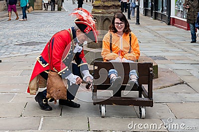 CHESTER, UK - 26TH JUNE 2019: The town crier locks up a tourist in a stockade in the middle of the city, summer 2019 Editorial Stock Photo
