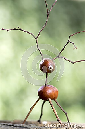 Chestnut animal on wooden stump, deer made of chestnut, acorn and twigs, green background Stock Photo