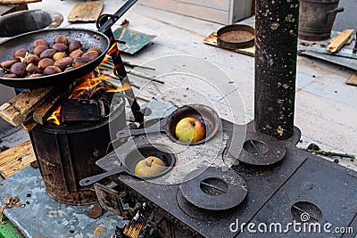 Chestnuts roasting in a hair on an old, vintage wood stove, in flames Stock Photo