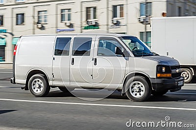 Chevrolet Express GMT610 driving on the street. Gray full-size van GMC Savana in motion on city road Editorial Stock Photo