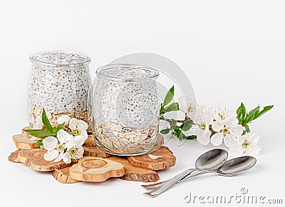 Chia seed pudding with yogurt and oats on white background decorated with flowers. Superfood concept. Stock Photo