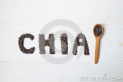 Chia seeds. Chia word made from chia seeds with spoon full of chia on white wooden background. Stock Photo