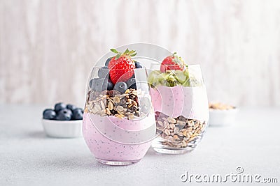 Chia seeds pudding with granola, blueberry and strawberry in glasses. Yogurt with chia seeds, berries, kiwi and muesli for healthy Stock Photo