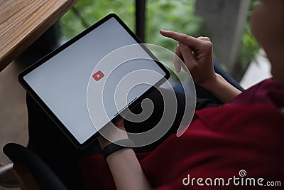 Chiang mai, Thailand - AUG 09, 2021 : Woman using a tablet to connect to YouTube Premium. YouTube is a video-sharing Editorial Stock Photo