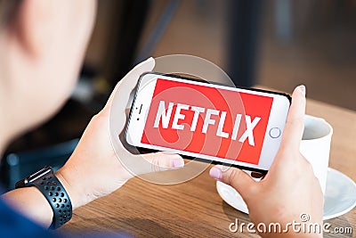 Chiang Mai / Thailand - June 22 2019 : Hands holding mobile with netflix screen in coffee shop Editorial Stock Photo