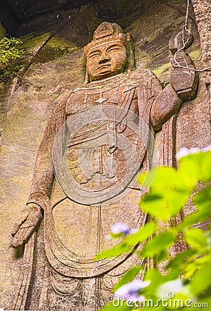 Low angle on the hyaku-shaku kannon buddha of Mount Nokogiri with a purple hydrangeas flower. Editorial Stock Photo