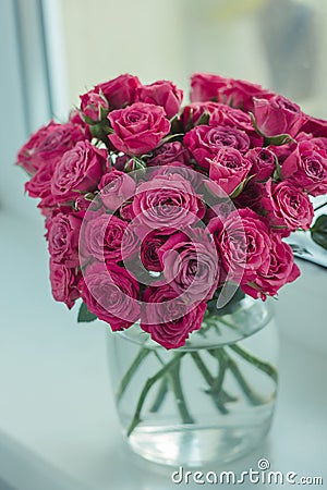 A chic bouquet of small pink roses in a jar on the windowsill. Cute still life Stock Photo