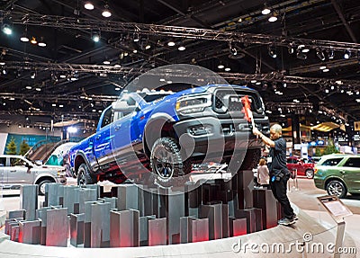 Male person dusting an elevated blue RAM pickup truck displayed at the Chicago Auto Show Editorial Stock Photo