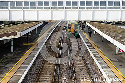 02/05/2020 Chichester, West sussex, UK Train passengers waiting on a railway station platform while a train arrives Editorial Stock Photo