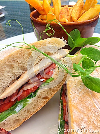 Chicken bacon lettuce and tomato sandwich in ciabatta bread with golden chips Stock Photo