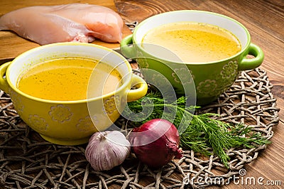 Chicken bouillon in the bowls on the rustic wooden background. Stock Photo