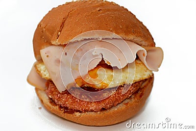 Chicken breast burger with fried egg, tomato slice, smoked turkey ham in a bun bread sandwich with ketchup and mayonnaise, Stock Photo