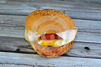 Chicken breast burger with fried egg, tomato slice, smoked turkey ham in a bun bread sandwich with ketchup and mayonnaise, Stock Photo