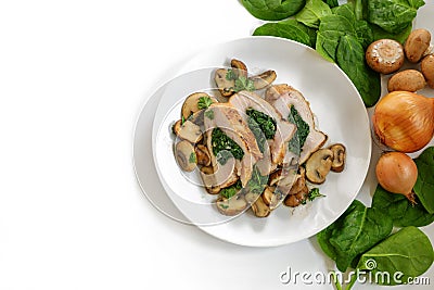 Chicken breast fillet with spinach filling, mushrooms, onion and parsley garnish on a plate, some raw ingredients, white Stock Photo