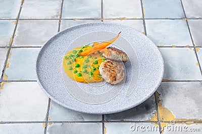 Chicken cutlet with pumpkin puree and green pies, decorated with carrots on tile background Stock Photo