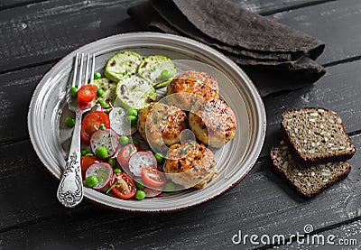 Chicken cutlets and fresh vegetable salad on ceramic plate on dark wooden background. Stock Photo