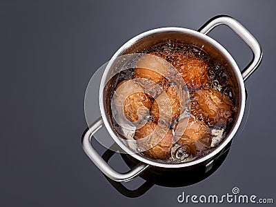 Chicken eggs are boiled in a saucepan on a glass ceramic induction hob. Cooking hard boiled eggs in a metal pan on electric stove Stock Photo