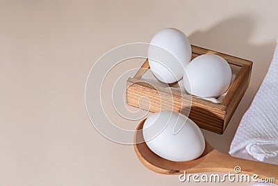 Chicken eggs in a wooden box on beige background with copy space, product with amino acids choline lecithin cholesterol calcium Stock Photo