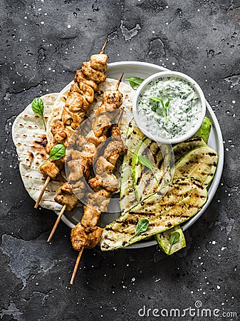 Chicken greek souvlaki, grilled zucchini, flatbread and tzadziki sauce - delicious lunch, tapas on a dark background, top view Stock Photo