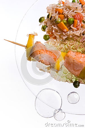 Chicken kebab with rice and vegetables on a white background on a transparent plate decoratet with glass stones Stock Photo