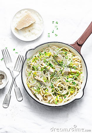 Chicken, leek, linguine pasta carbonara in a frying pan on a light background, top view. Flat lay Stock Photo