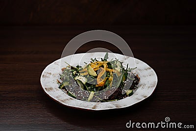 Chicken liver salad with fresh cucumber slices with bell pepper with arugula in honey sauce with sesame on a wooden table Stock Photo