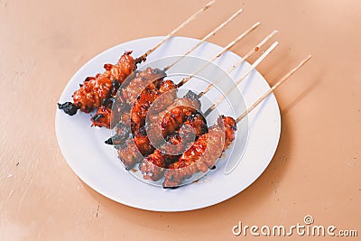 Chicken Satay or Chicken skin satay with red spices on white plate isolated on wooden tables Stock Photo