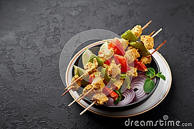 Chicken Tikka at skewers in black bowl at dark slate background. Chicken tikka is an indian cuisine dish. Indian food Stock Photo