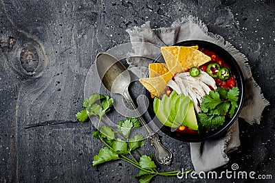 Chicken tortilla chili soup with nachos, avocado, lime, jalapeno. Mexican traditional dish. Stock Photo