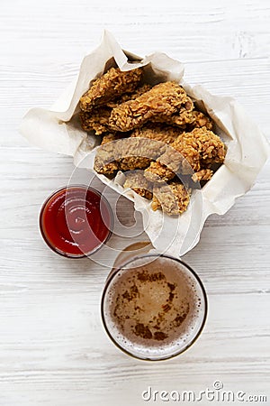 Chicken wings with ketchup, cold beer over white wooden background, top view. From above, overhead. Stock Photo