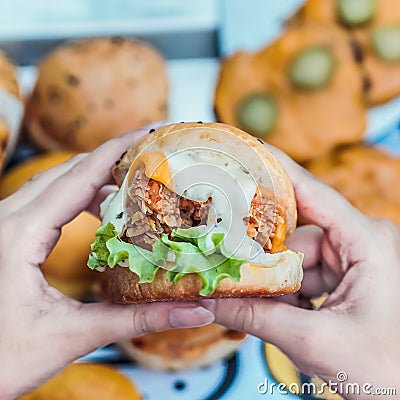 Chicken zinger burger filled with mayo sauce cheese and vegetables in a hand Stock Photo