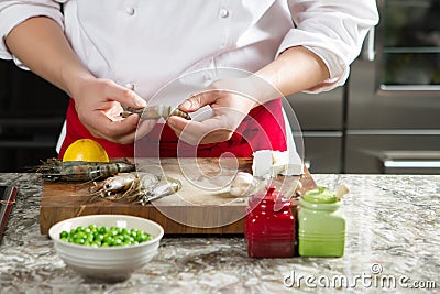 Chief cook in the kitchen prepares royal shrimps Stock Photo