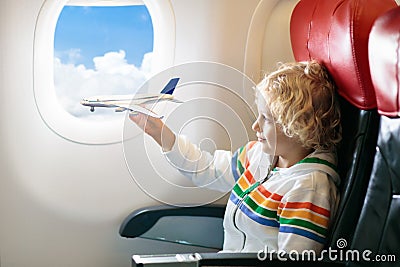 Child in airplane. Kid in air plane sitting in window seat. Flight entertainment for kids. Traveling with young children. Kids fly Stock Photo