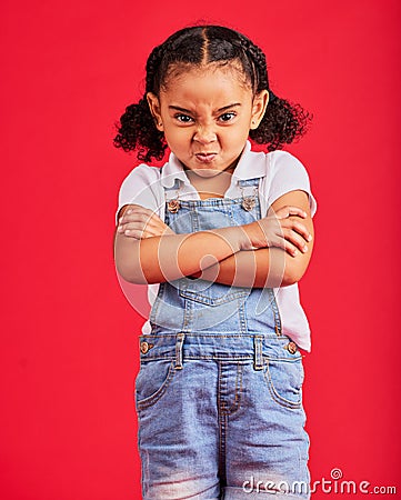 Child, arms crossed or angry portrait on isolated red background for tantrum face, behavior problem or stubborn. Mad Stock Photo