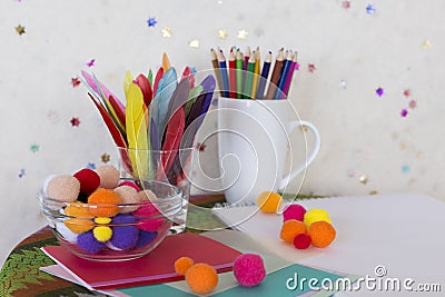 Child arts and craft work station with colored pencils, colourful feathers, pom poms and paper Stock Photo