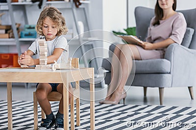 A child with Asperger Syndrome playing with wooden blocks during a therapeutic meeting with a therapist in a family support center Stock Photo