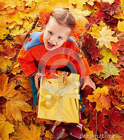 Child in autumn orange leaves and gift box. Stock Photo