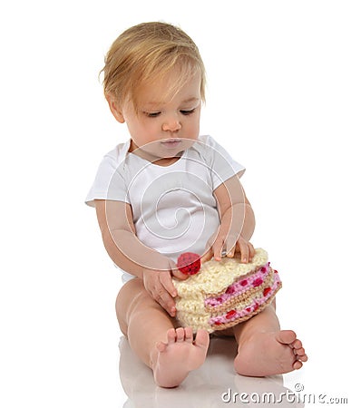 Child baby girl toddler sitting holding piece of candy cake toy Stock Photo