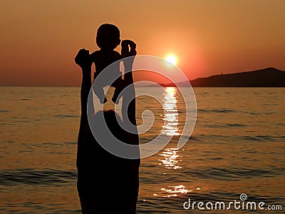 Child with baby toys in sunset on sea Stock Photo