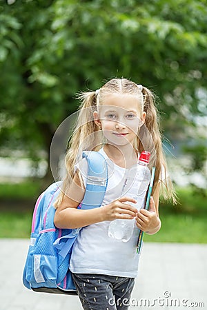 A child with a backpack and a bottle of water. The concept of school, study, education, friendship, childhood. Stock Photo