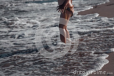 A child on the beach.Children`s feet on the background of the contrasting sun are immersed in the sand, which is washed by a wav Stock Photo