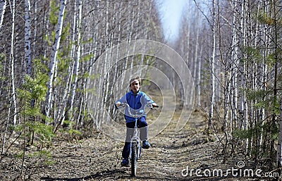 Child on a bicycle on a forest road Stock Photo