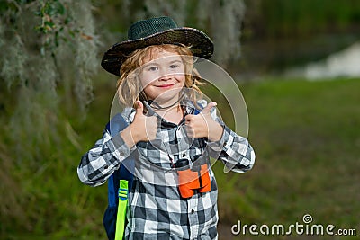Child with binoculars travelling outdoors. Boy traveler with backpack in a summer day. Portrait of a little boy Stock Photo