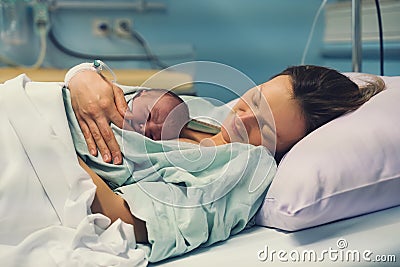 Child birth in maternity hospital. Mother and newborn. Young mom hugging her newborn baby after delivery. Woman giving birth Stock Photo