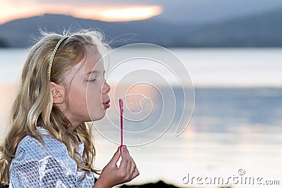 Child blowing bubbles by the sea Stock Photo