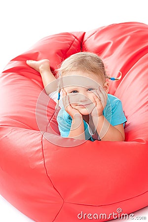 Child in blue shirt on red pouf chair Stock Photo