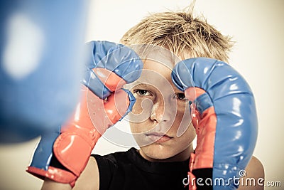 Child with boxing gloves focusing on punching pad Stock Photo